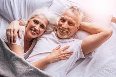 Happy elderly couple lying in bed together