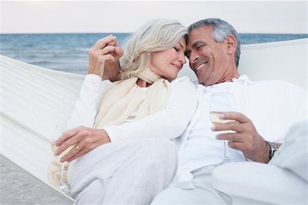 Happy elderly couple relaxing on a beach hammock