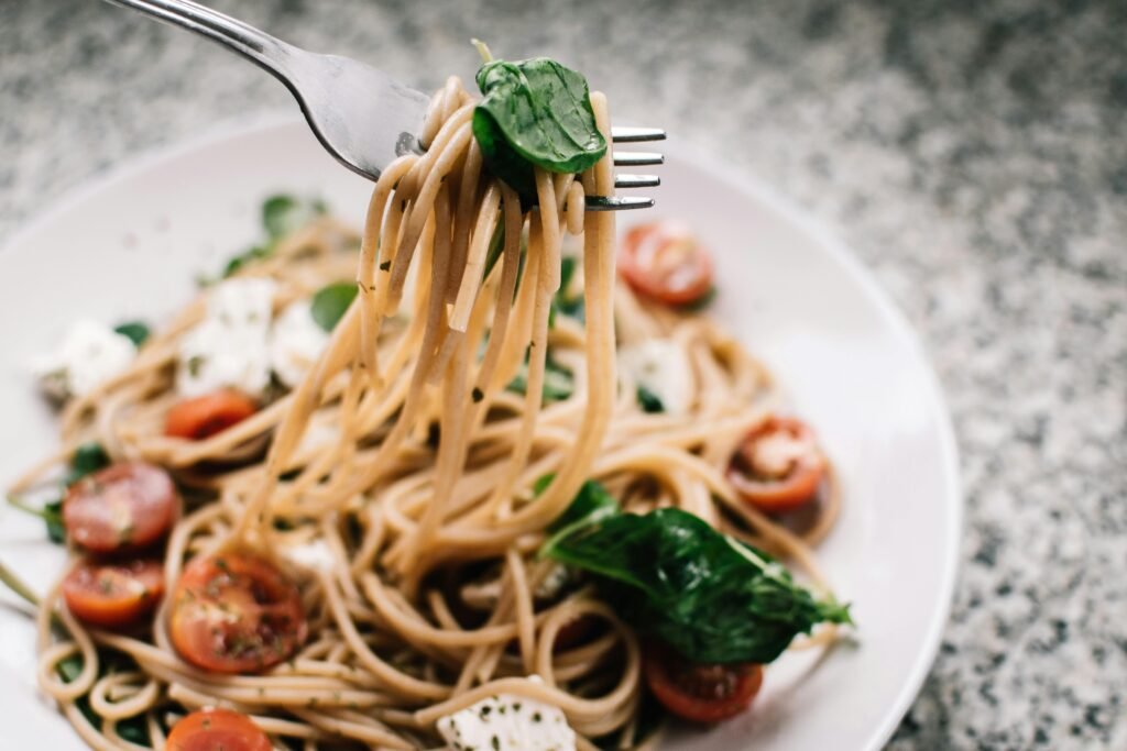 pexels-photo-1279330-1279330 Delicious whole wheat pasta with fresh spinach, cherry tomatoes, and feta cheese in a close-up shot.