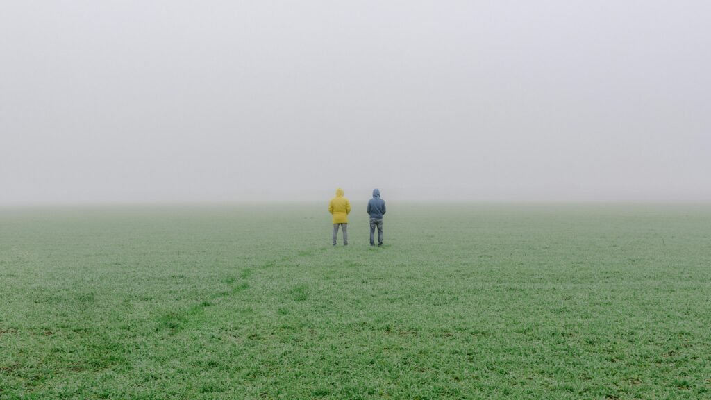 pexels-photo-3027407-3027407 Two people in hooded jackets stand in a foggy grass field