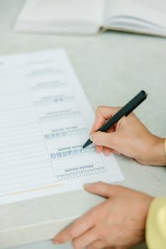 pexels-photo-8844562-8844562 Hands filling out a nutrition plan with a focus on water intake. Ideal for health and wellness themes.