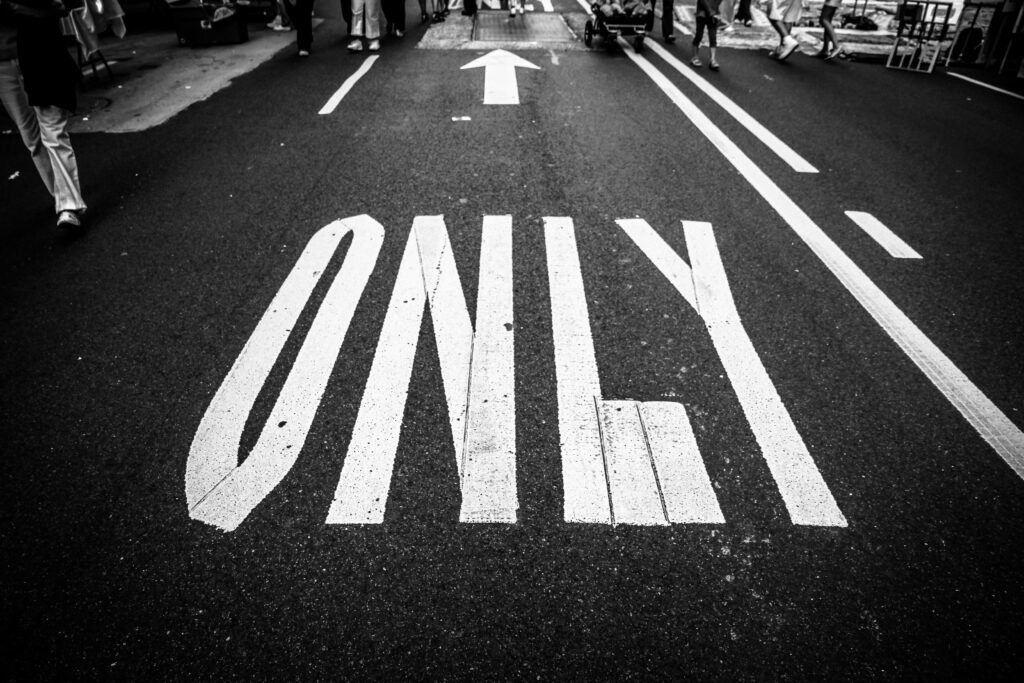 Path Forward Black and white photo of road, showing traffic markings, a crowd, and an arrow.