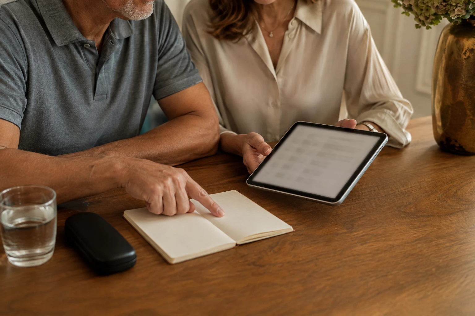 A couple comparing purchase details using a tablet and notebook