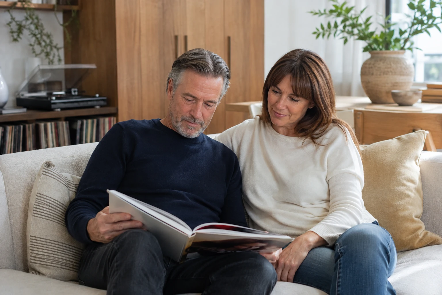 Couple sharing an art book on a bright living-room sofa