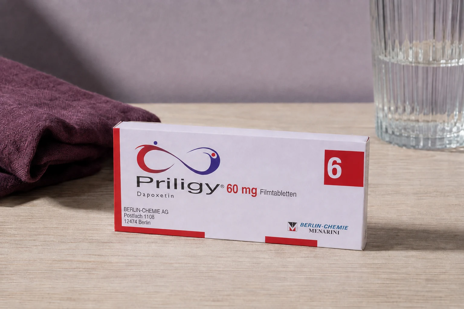 Priligy 60 mg dapoxetine carton beside plum linen and a ribbed glass of water