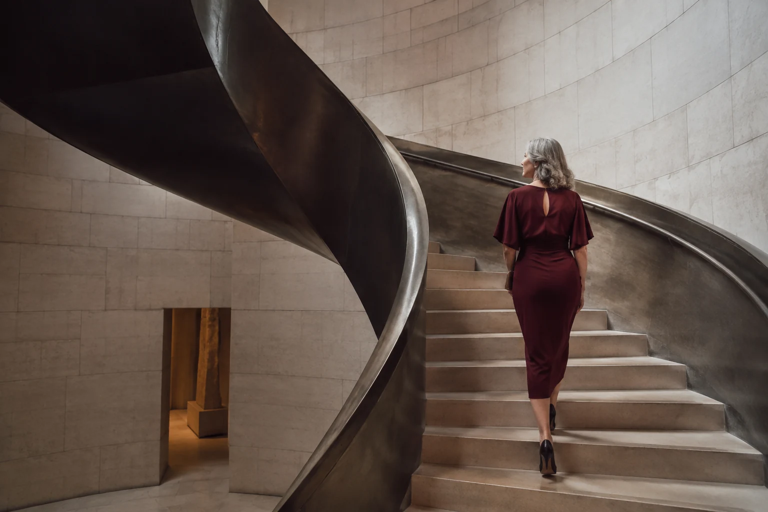 Woman in a burgundy dress ascending a sculptural limestone staircase