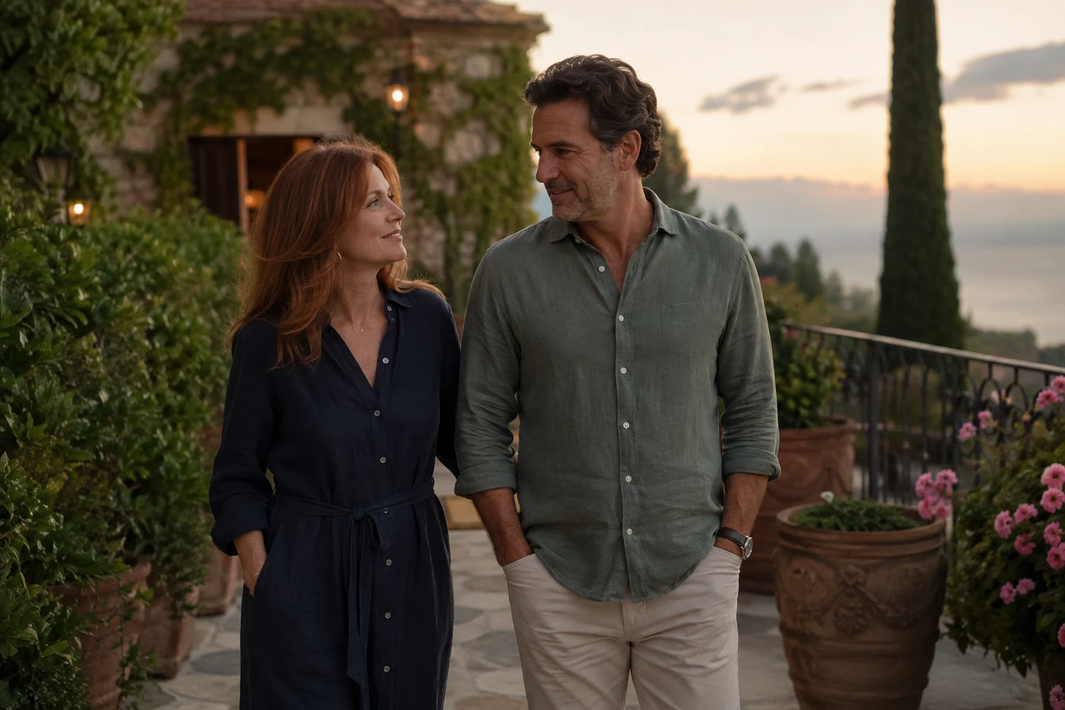 An adult couple walking together on a garden terrace at dusk