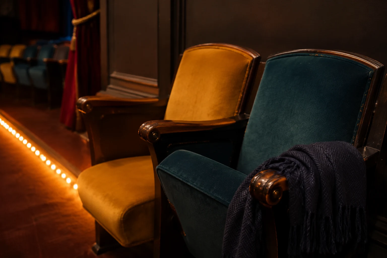 Teal and ochre theatre seats with a navy scarf in warm evening light