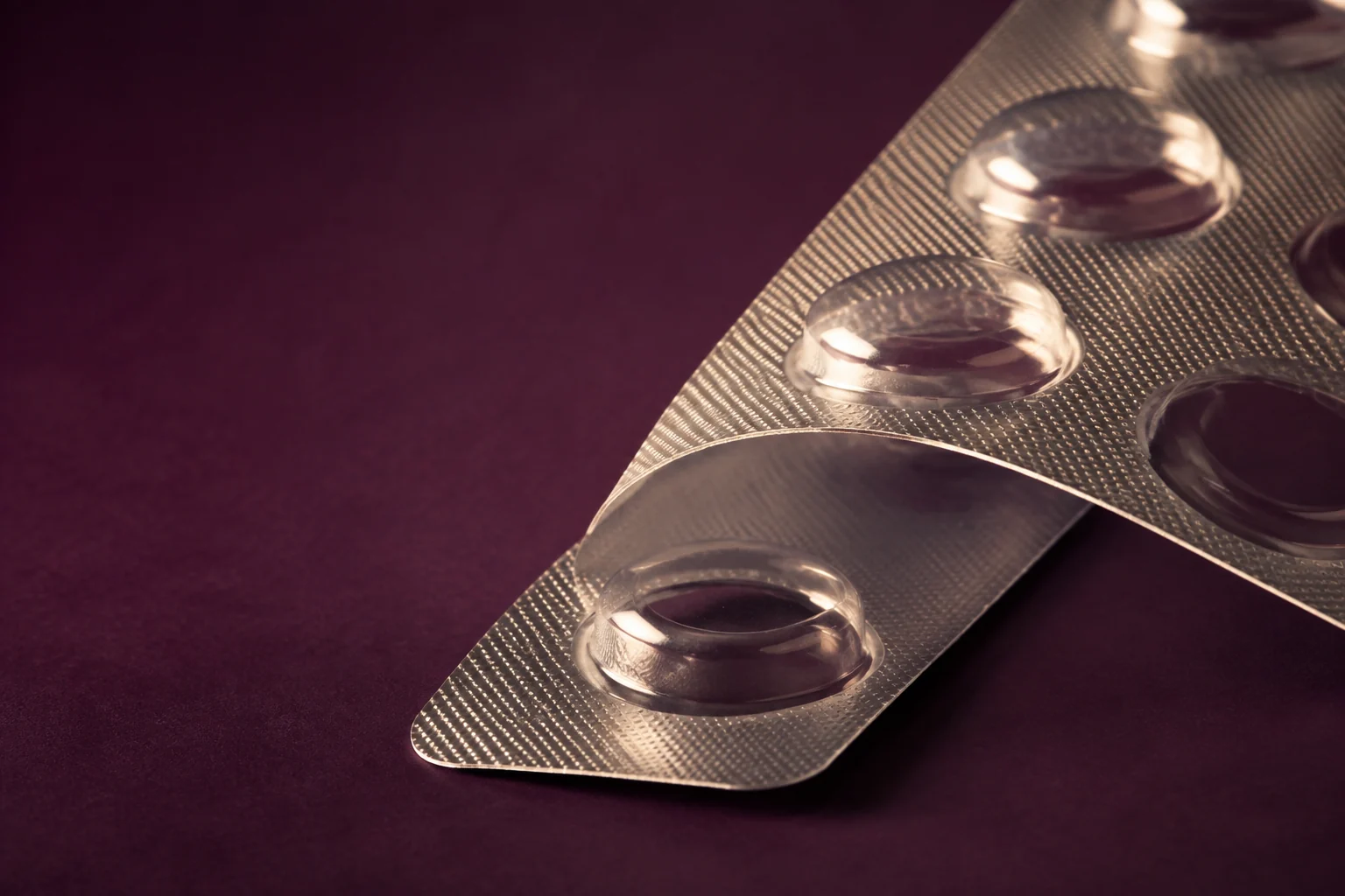 Macro view of unprinted silver blister packaging on a plum surface