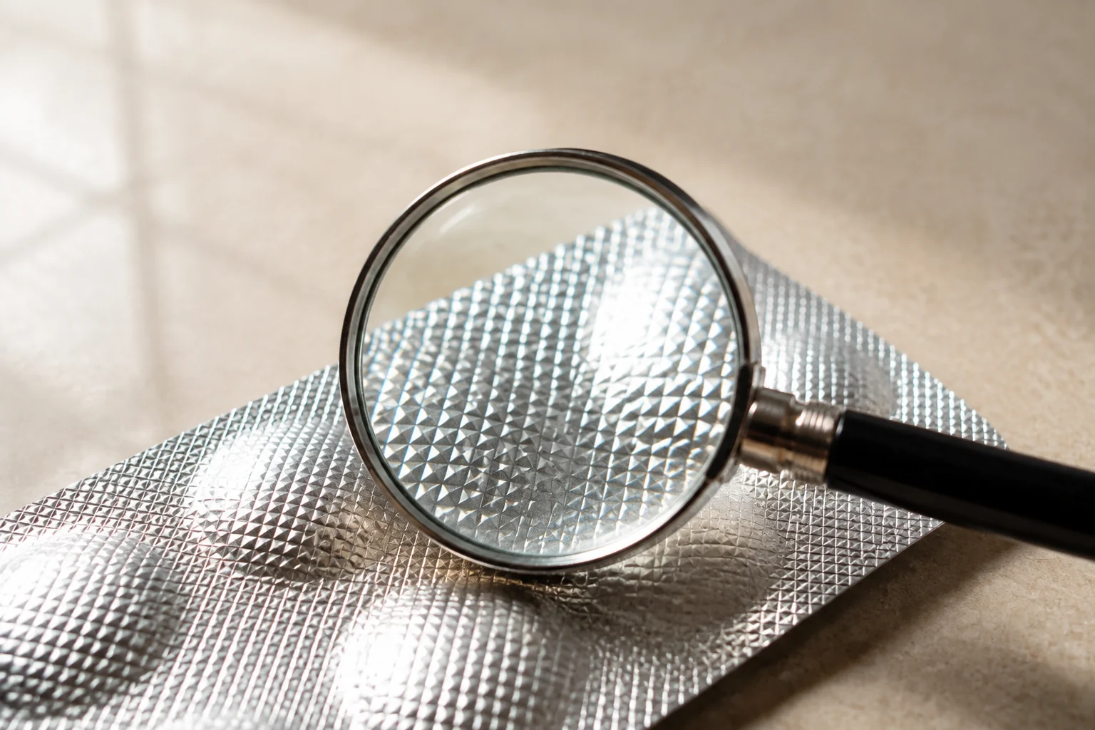 A magnifying lens enlarging the texture of silver pharmaceutical foil