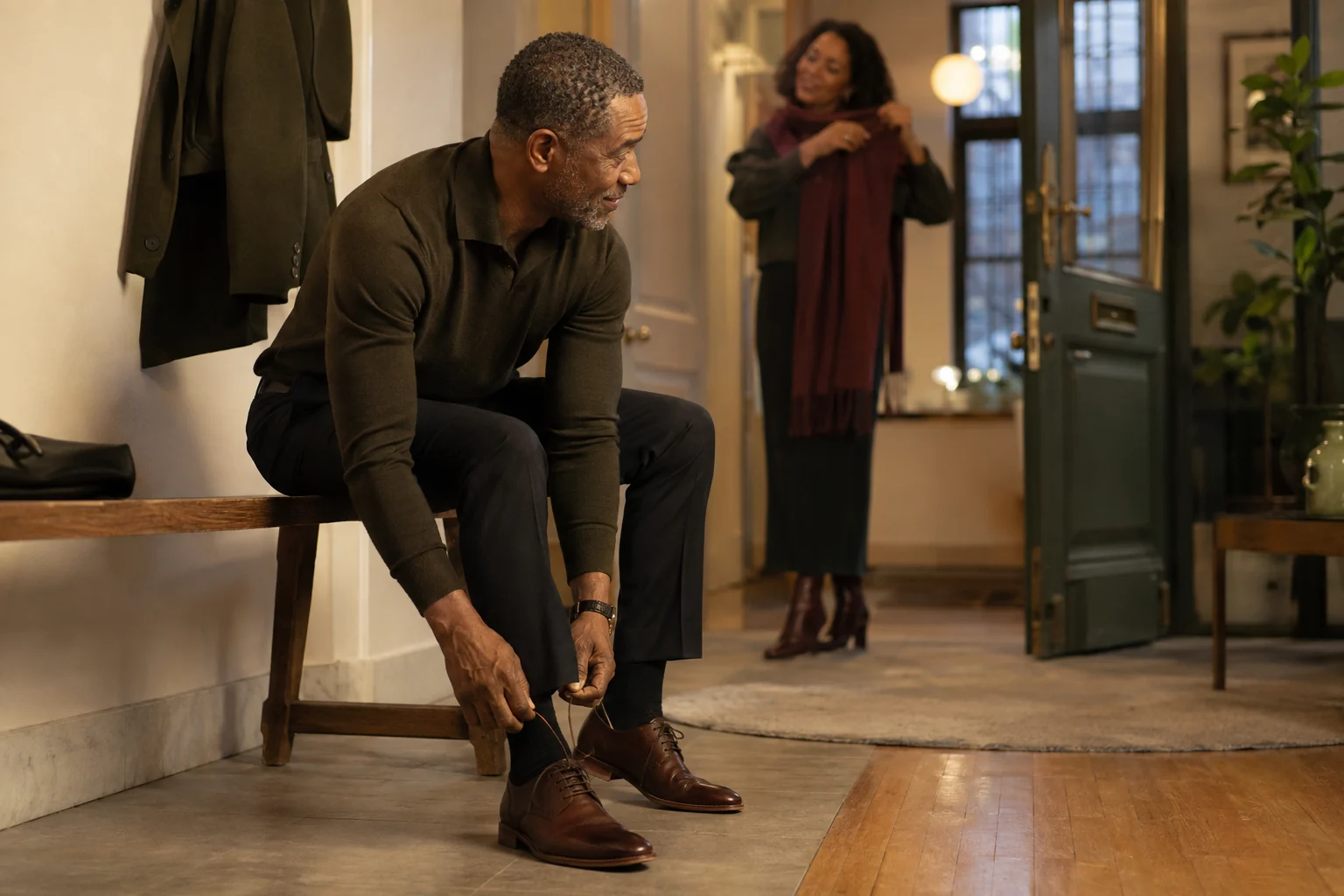 Mature man finishing his shoes while his partner prepares for an evening out