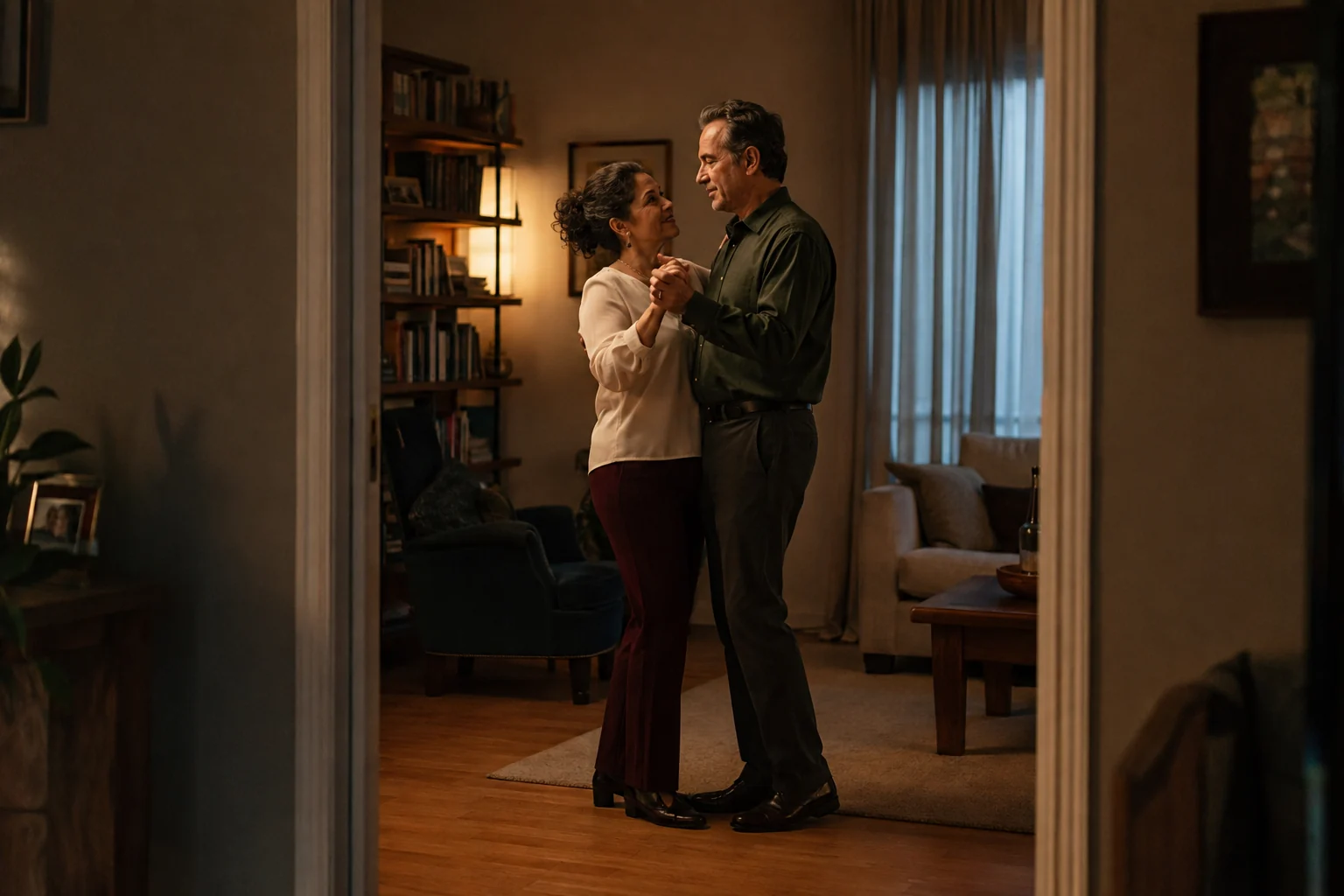 Mature couple sharing a quiet dance in their living room at dusk