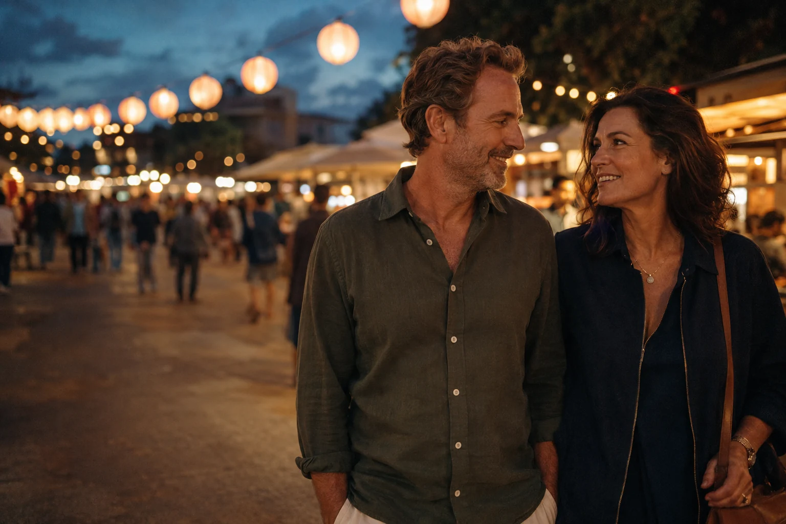 A mature couple enjoying a walk through an evening market under warm lanterns