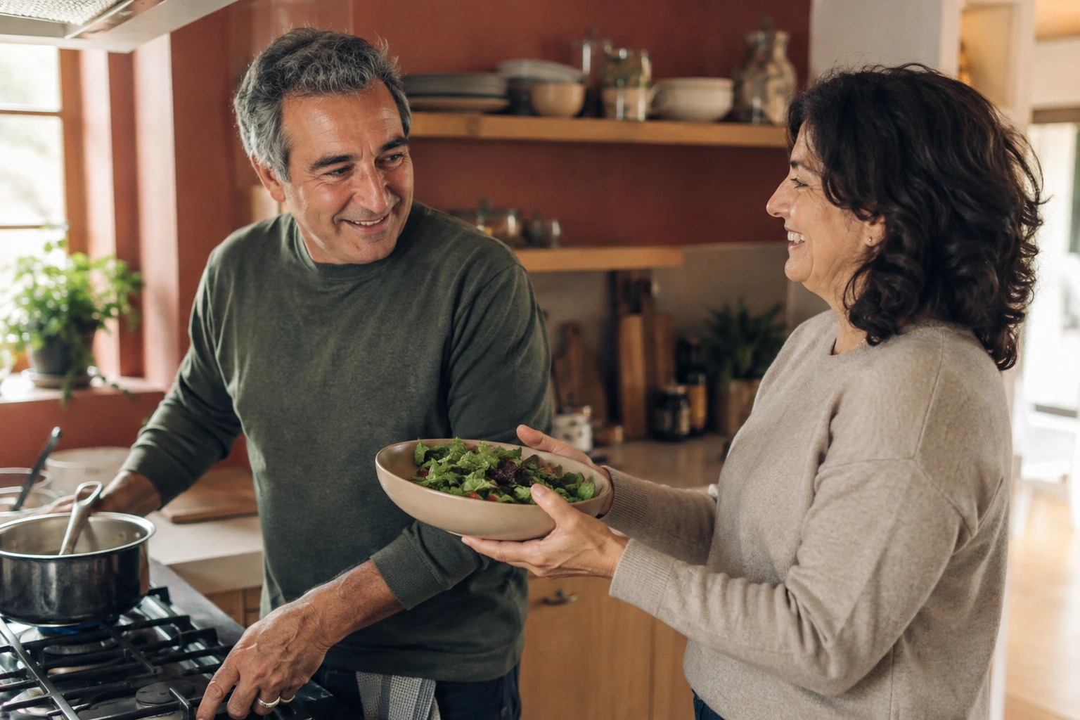 An adult couple share a laugh while preparing dinner together.